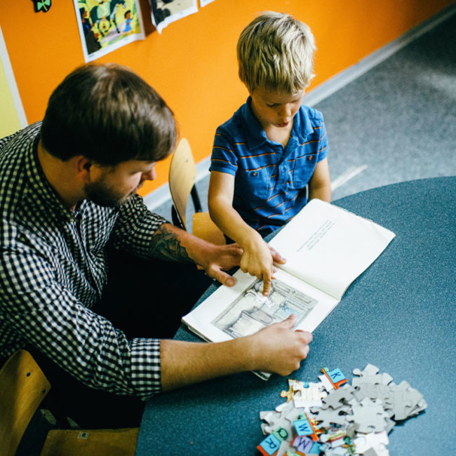 Graduate of education assistant course with child in classroom.