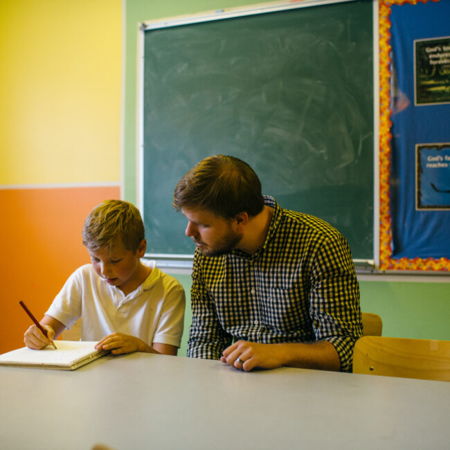 Graduate of education assistant course with child in classroom.