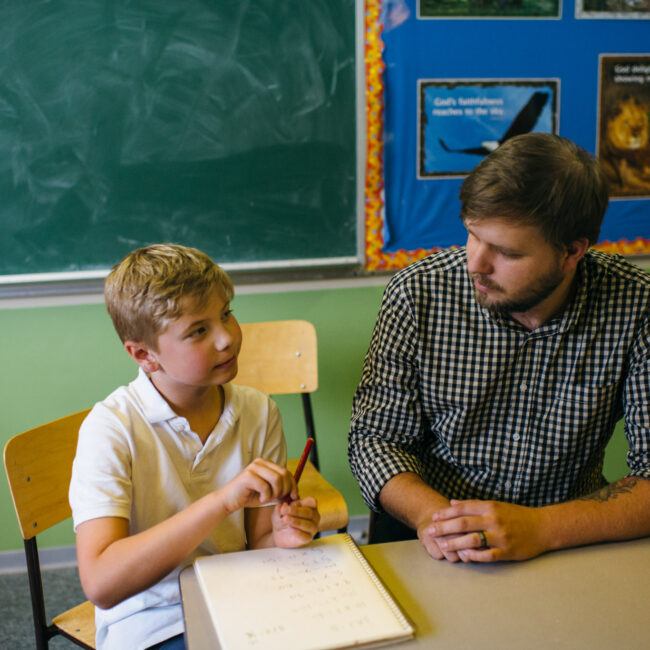 Graduate of education assistant course with child in classroom.