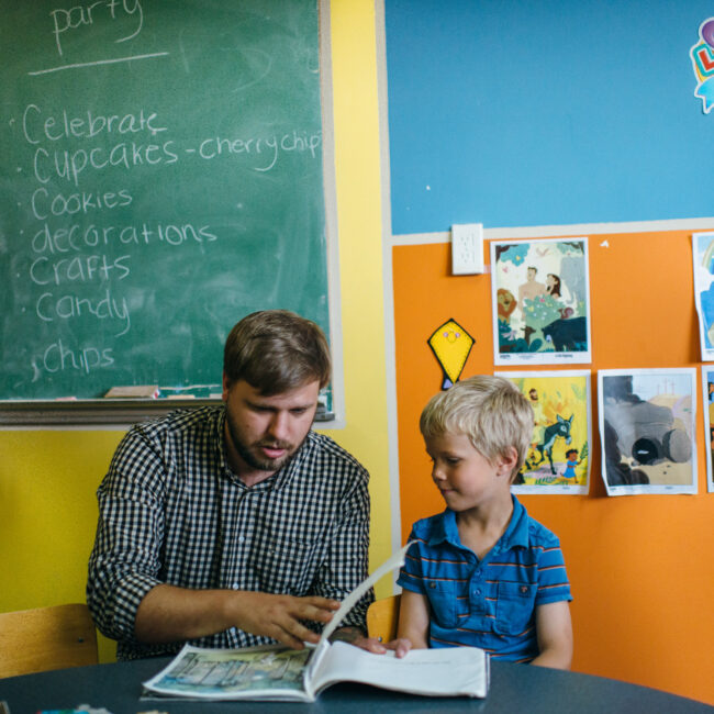 Graduate of education assistant course with child in classroom.