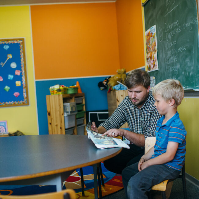 Graduate of education assistant course with child in classroom.