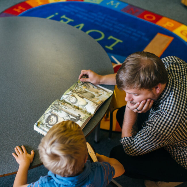 Graduate of education assistant course with child in classroom.