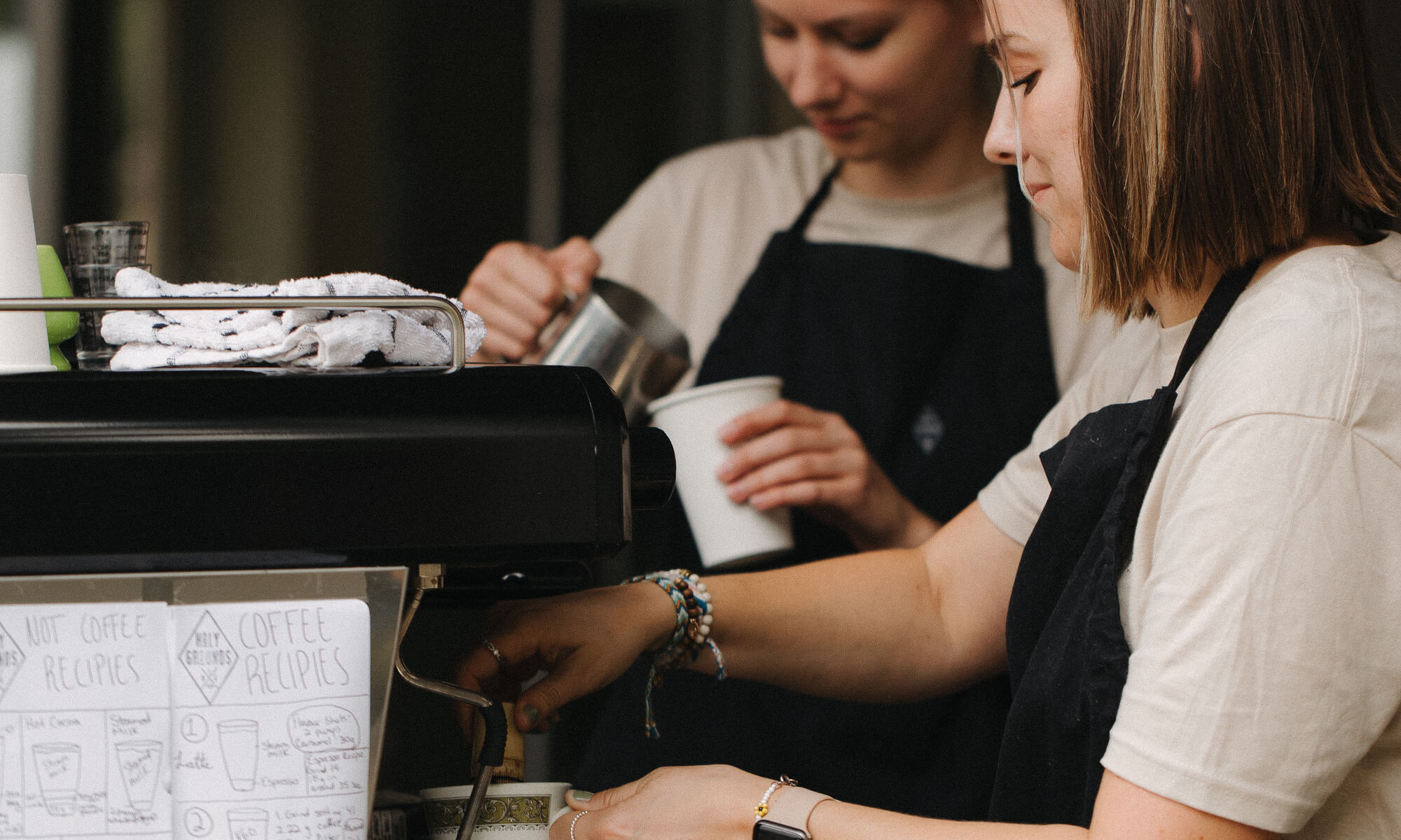 two women make coffee at an espresso machine